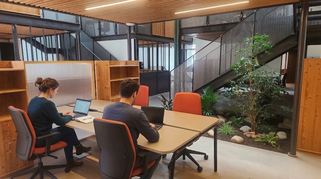 Deux coworkers installés à leur poste fixe dans l'open space végétalisé Chez NOO à Oullins, près de Lyon.