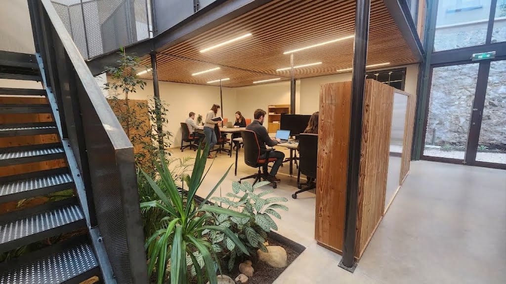 Espace de coworking éco-responsable NOO à Oullins (Lyon Sud) montrant les aménagements en bois naturel, la végétation intérieure et les postes de travail baignés de lumière naturelle à 100m du métro B.