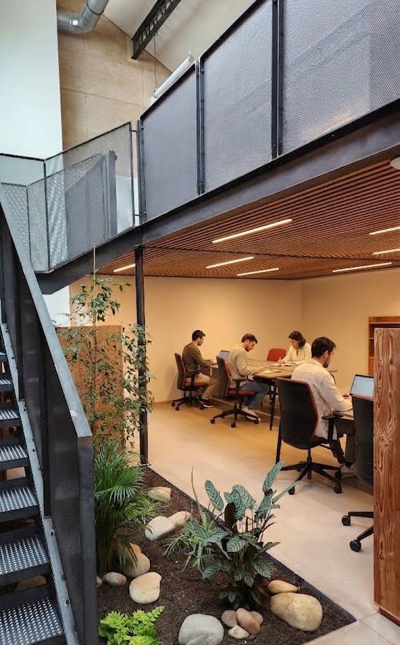 Des coworkers installés à leurs postes de travail dans l'espace de coworking végétalisé et industriel Chez NOO à Oullins.