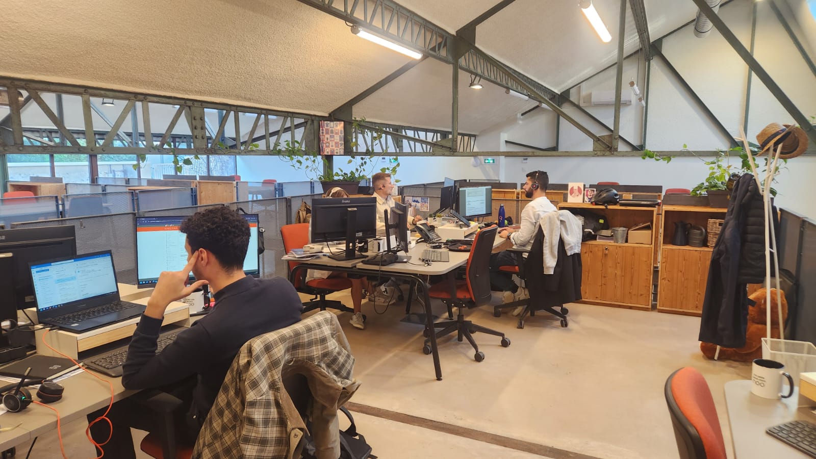 Espace de coworking avec postes fixes équipés et plantes grimpantes sur structure métallique chez NOO à Oullins